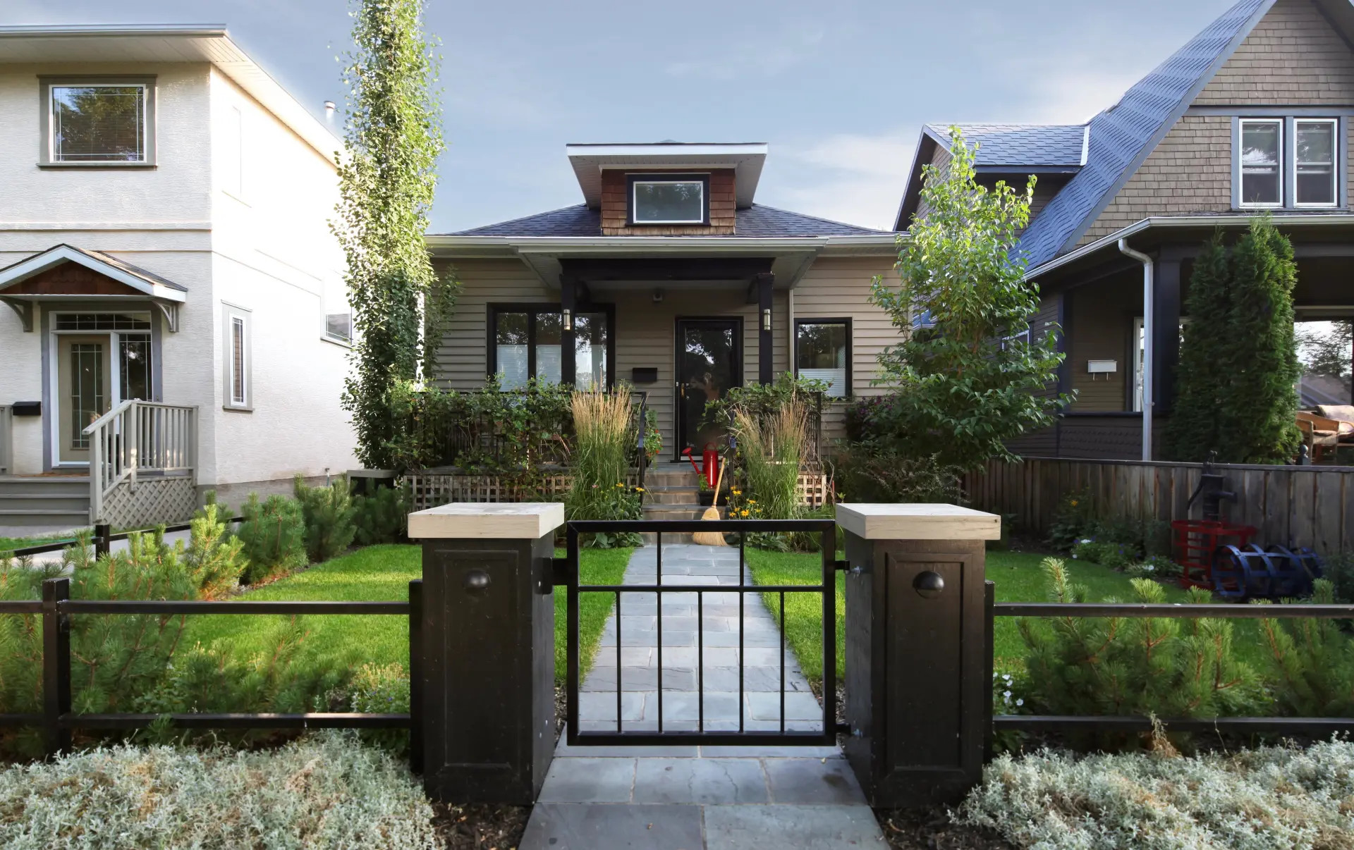 Image of a single family home from the sidewalk with a small gate at the edge of the front yard 