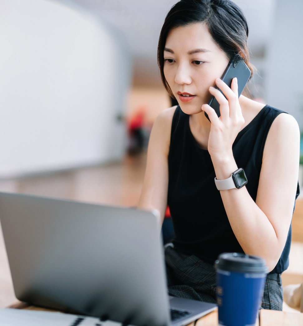 Image of a woman on the phone working on her laptop