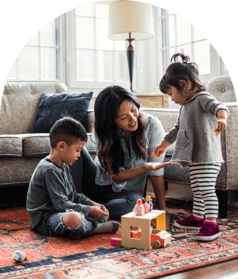 Mother and her two children playing with toys in the living room on the rug